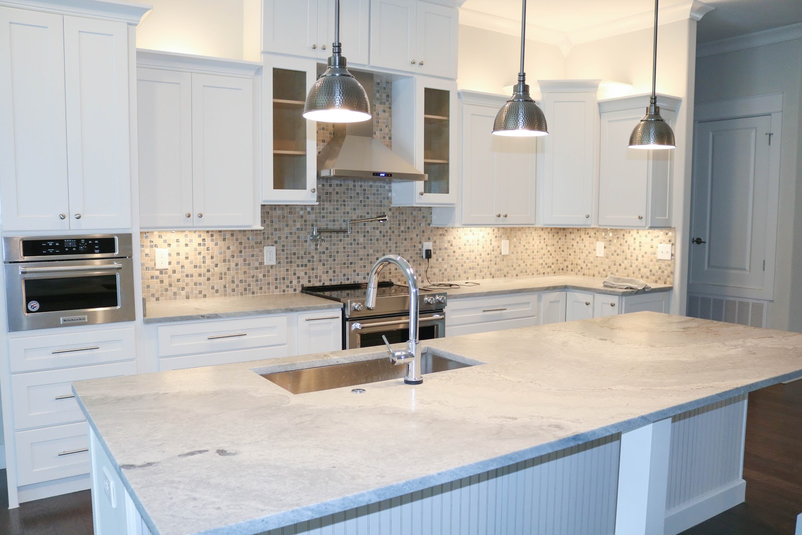 Kitehenaia Beautiful kitchen with a large island and white cabinets and a light backwash.